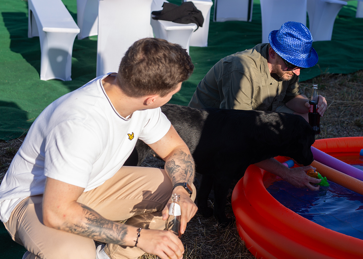 Zwei Männer mit Hund an einem Kinderpool